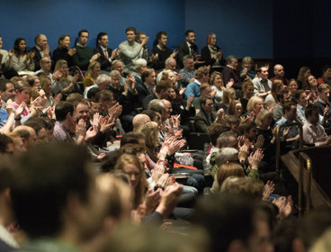Audience in a theatre clapping.