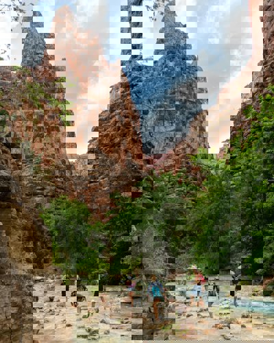 Three people walking next to the Colorado river