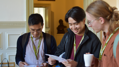 Three people talking at conference. They're looking at a sheet of paper.