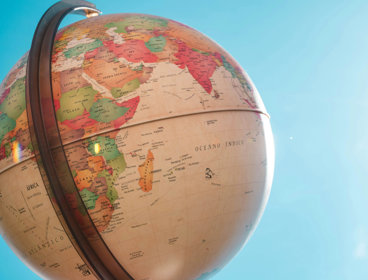 Globe with blue sky and the sun in the background.