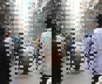 Streetscene with people and large bronze ball sculpture being wheeled along the street