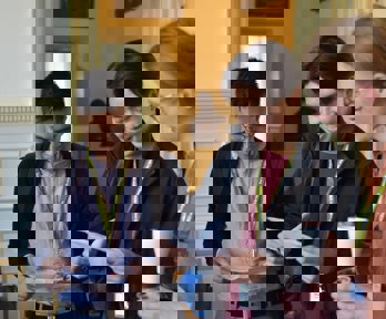 Three people looking at a conference programme and holding coffee cups