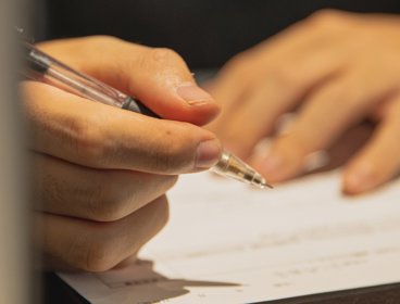Person writing with a pen on paper.