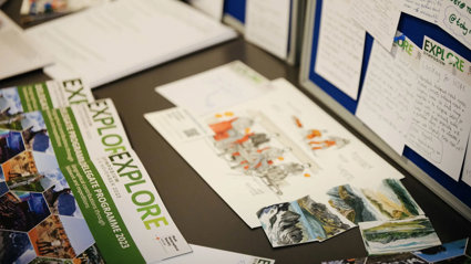 Tabletop full of images of mountains and leaflets from the Society's Explore symposium 2023. One of the leaflets reads Delegates programme 2023.