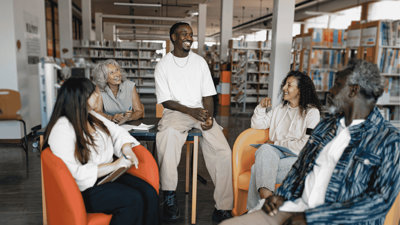 Group of five people sat in chairs in community library.