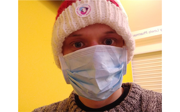 Mark Green wearing a blue medical facemask and a beanie. The beanie has sticker on it that reads 'I've had my COVID vaccination'.