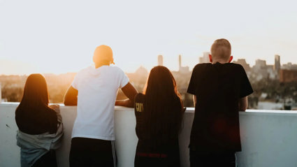 Four young people looking at a city view with their backs to the camera.