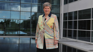 A woman wearing a coat with a map printed on it standing in front of a modern building.