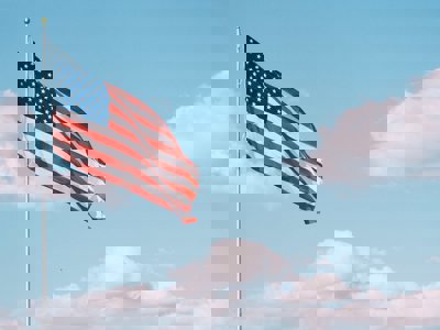 Amercian flag on blue sky and clouds background
