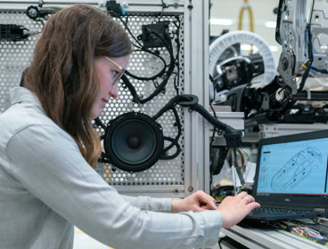 Engineer sitting at a computer in a factory looking at plans to build a car.