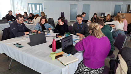 People sitting at tables at a workshop event.