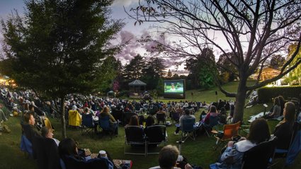 A fisheye shot of people sitting in camping chairs at an outdoor film screening.