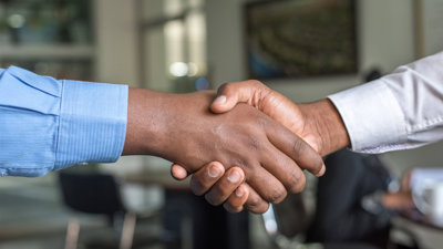 Two people shaking hands with only the hands in view. 
