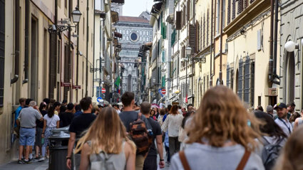 Tourists walking down a busy city street in Florence, Italy, on a summer's day.