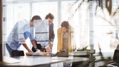 Three professionals leaning over a table looking at plans.