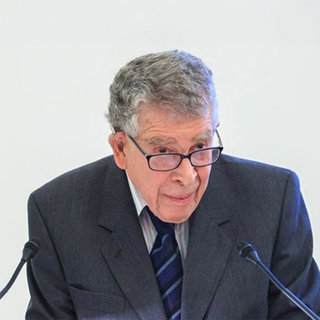 David Lowenthal in suit and tie in front of two microphones.