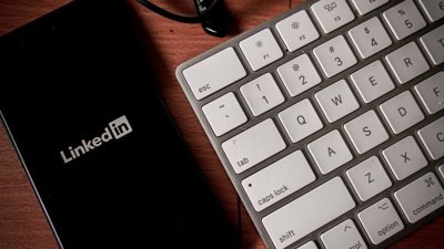 Phone displaying the LinkedIn logo, next to a keyboard.