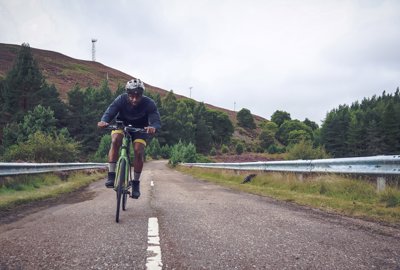 A man riding a bike down a highlands road