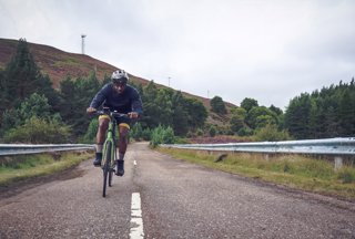 A man riding a bike down a highlands road