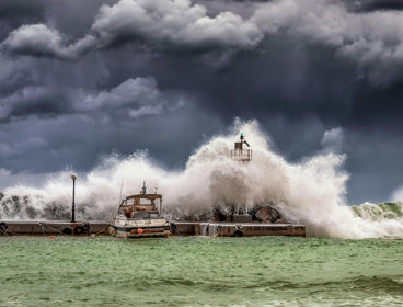 A boat is covered by waves from a stormy sea.