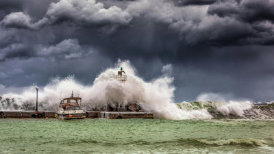 A boat is covered by waves from a stormy sea.