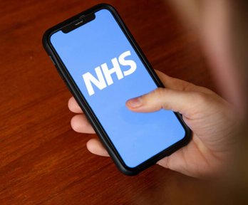 Person holding a phone with NHS logo in white with blue background.