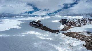 A wide, barren, mountainous landscape covered in snow.