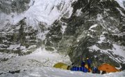 Expeditioners having breakfast at base camp at the foot of a mountain partially covered in snow and ice.