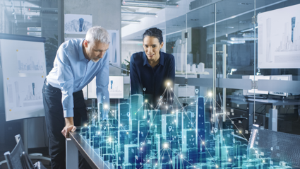 Two people watch over a digitised version of a city.