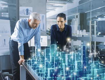 Two people watch over a digitised version of a city.