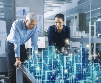 Two people watch over a digitised version of a city.