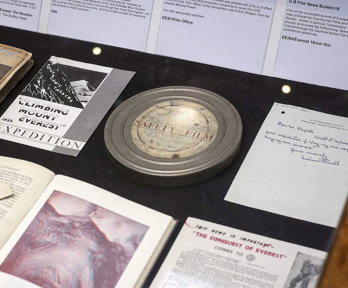 Display of historic materials, including a film reel, books, and advertisements.