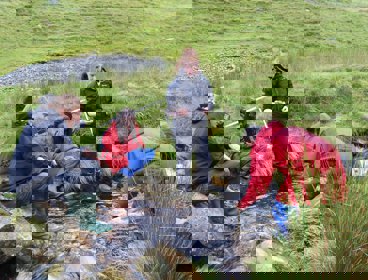 Group of pupils undertaking river fieldwork in a small stream.