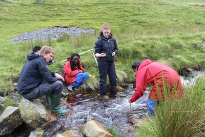 Group of pupils undertaking river fieldwork in a small stream.