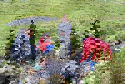 Group of pupils undertaking river fieldwork in a small stream.