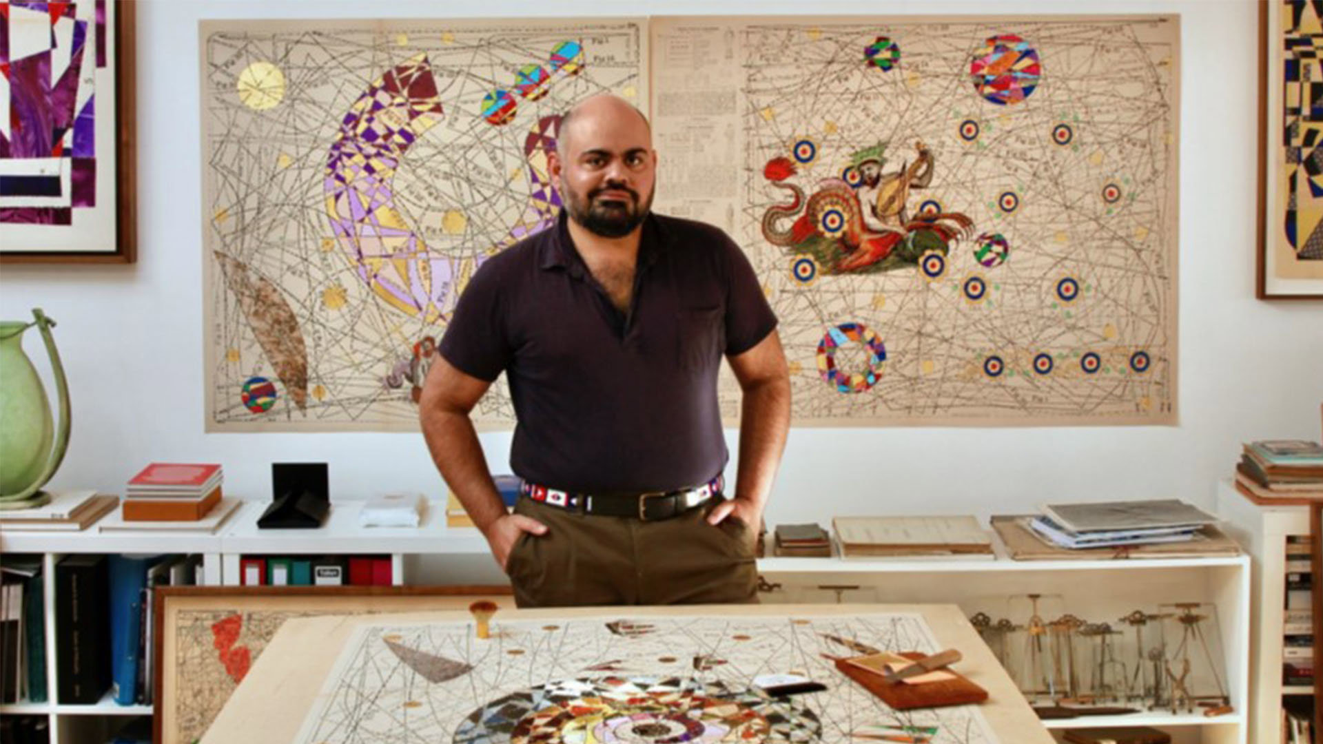 Photo of the artist Hormazd Narielwalla in his studio with abstract map artwork.