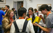 Four people at a conference standing in a circle. The two on the right each hold a bag that says 'firedepot'. The two on the left are watching them open the bags.