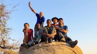 Group of people sitting on a rock and posing for a photo.
