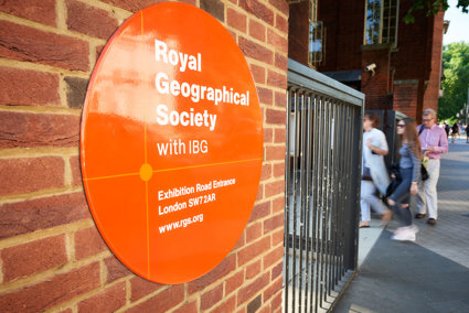 Sign on the outside of the Society's building close to the entrance, with three people walking in.