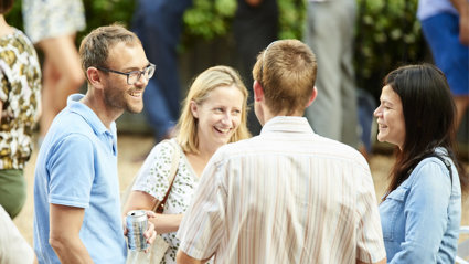 Group of four people standing in a circle chatting and smiling.