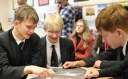 Three students looking at satellite glacier images on table.