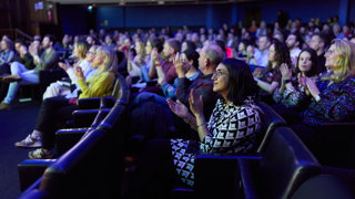 Audience members clapping during winter film night in the Ondaatje Theatre