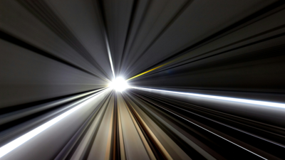 Blurred lines and central bright light depict high speed movment through a train tunnel.
