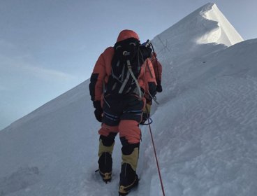 Person climbing a snow covered ridge on Mount Everest.