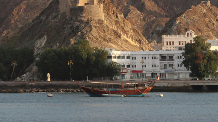 Boat on the sea by the coastline with a white building in the background.