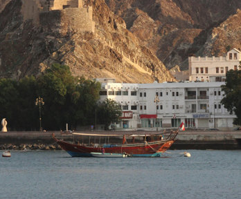 Boat on the sea by the coastline with a white building in the background.