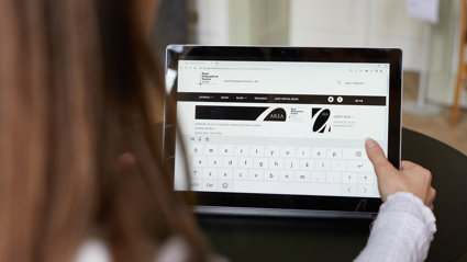 Close-up of a person holding a tablet displaying the website of the RGS-IBG's AREA journal. 