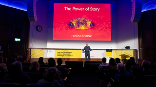 Frans Lanting presenting on stage during his lecture 'the power of story'.