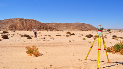 Researcher undertaking a topographic survey of an arid landscape using differential GPS equipment