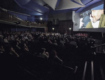 Audience watching a film in a dark theatre.